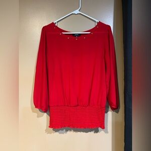 Women's red pullover blouse with a smocked waist and gold-tone stud details